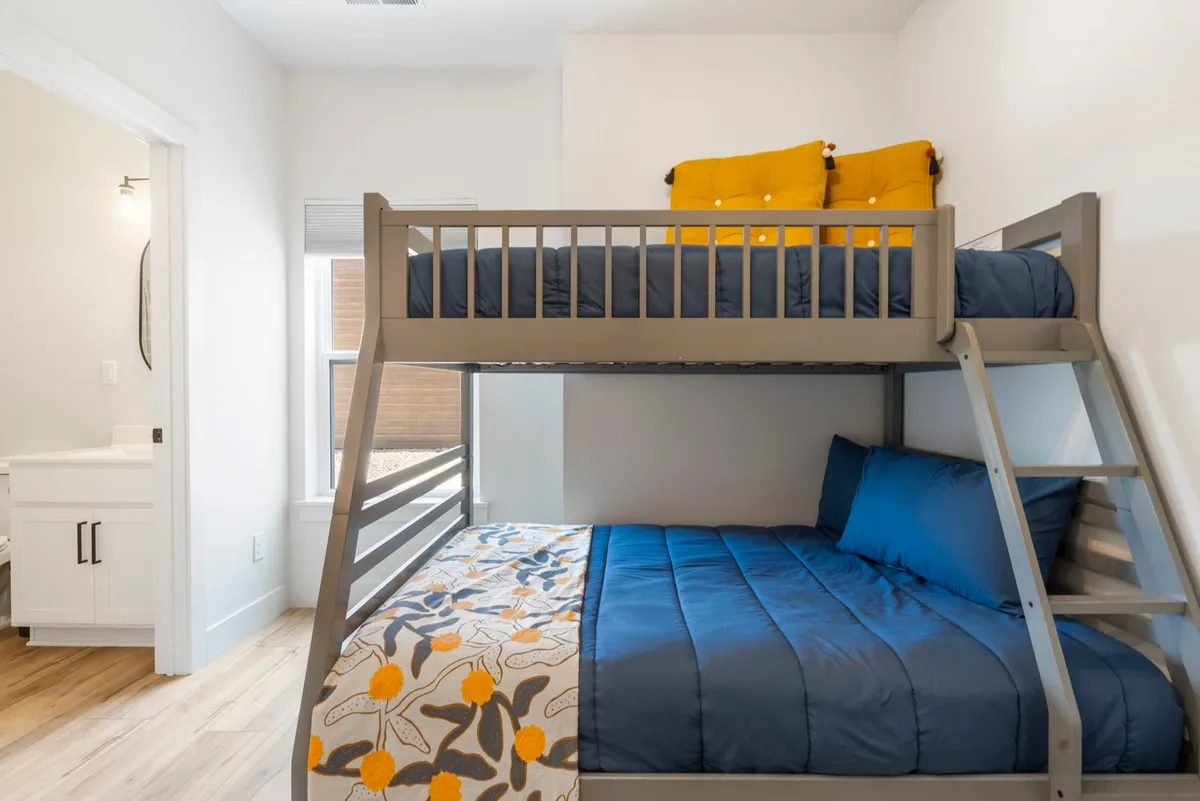 A cheerful bunk room featuring a bunk bed with colorful pillows and a decorative blanket, designed to be playful and inviting for children or teens.