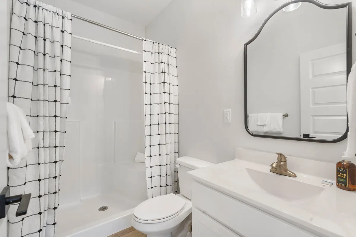A well-appointed bathroom with a mirror, sink, shower curtain, and neatly arranged towels, offering a sense of tranquility and privacy.