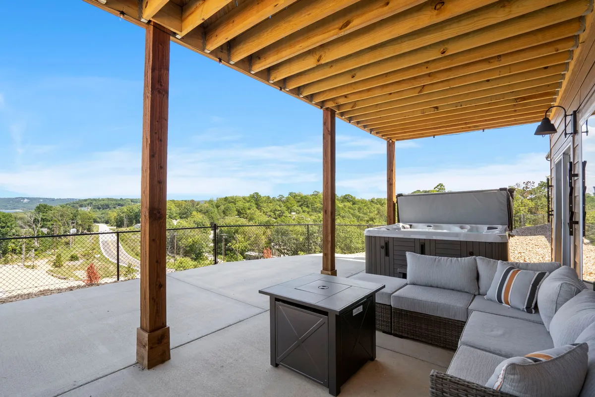 An outdoor hot tub situated on a patio with comfortable seating and wooden beams overlooking a scenic landscape. The setup invites both relaxation and socialization, blending indoor comfort with outdoor adventure.