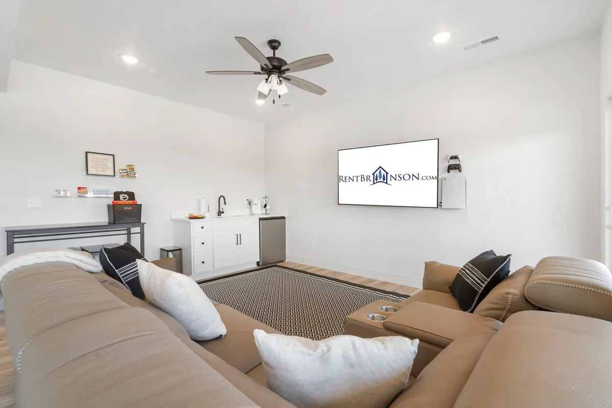 A modern, comfortable family room with a large sofa, television, and a bar area. The space feels inviting and perfect for relaxing, socializing, and enjoying movie or game nights with family and friends.